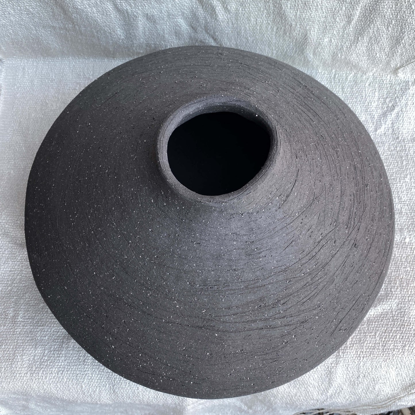 Black, wide belly ceramic decor vessel with stone texture.