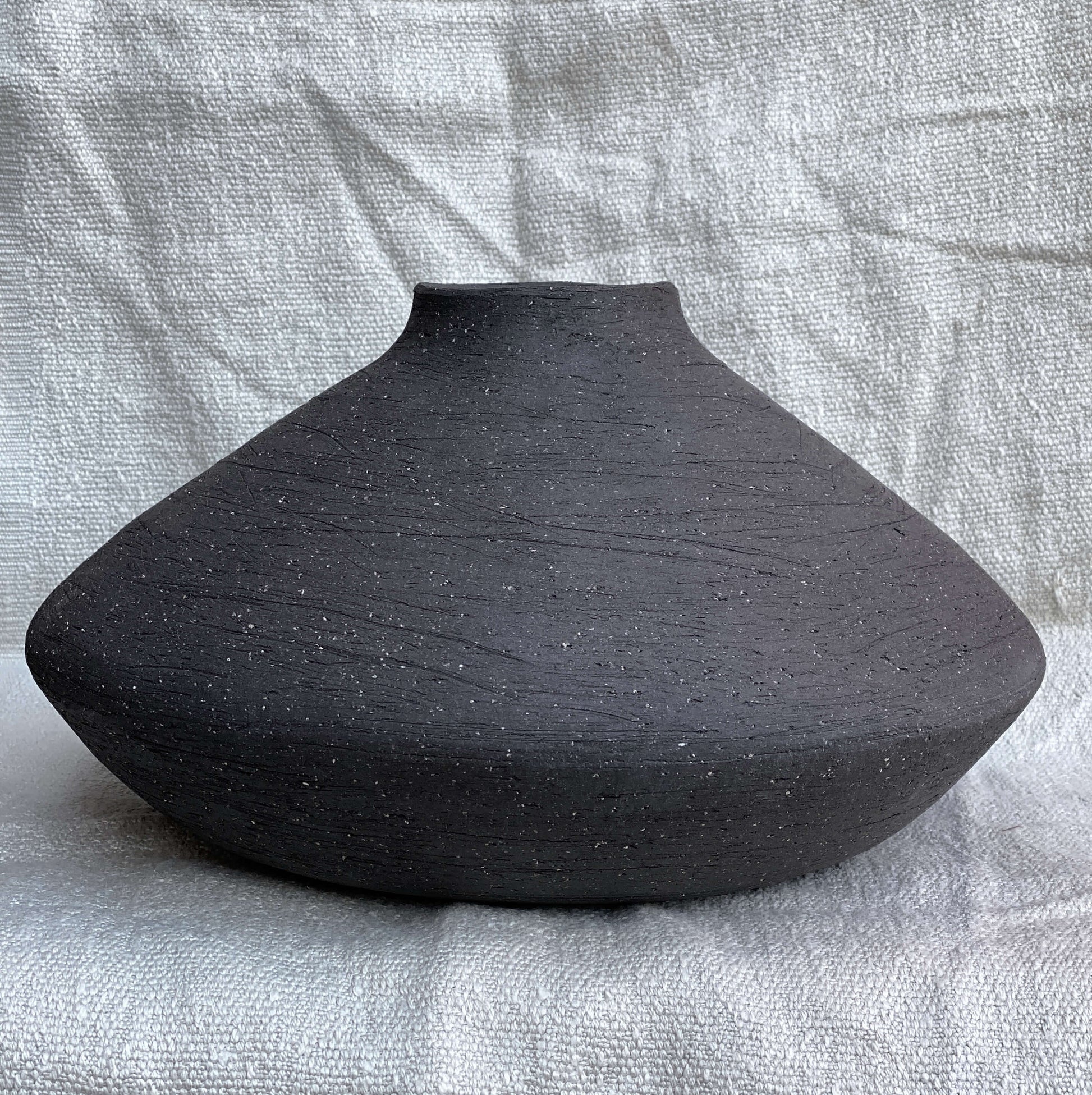 Black, wide belly ceramic decor vessel with stone texture.