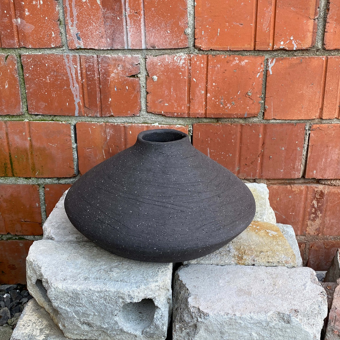Black, wide belly ceramic decor vessel with stone texture.
