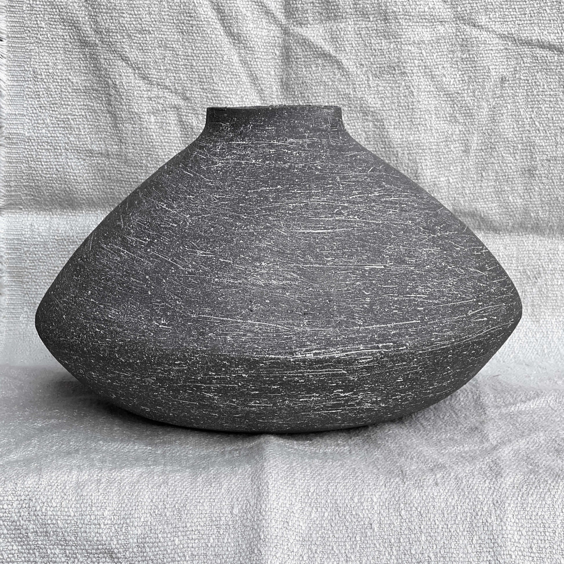 Black, wide belly ceramic decor vessel with white texture.