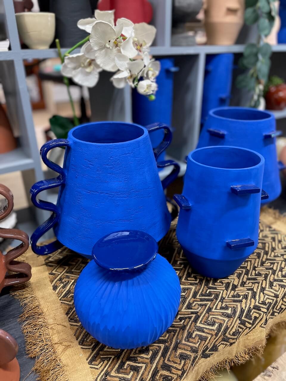 Set of blue ceramic vessels and a candle holder on a textured surface with a blurred background